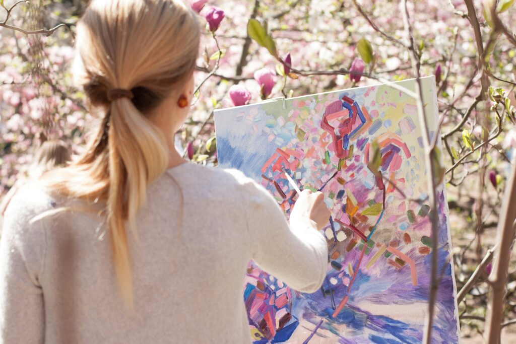 Woman painting on a canvas some magnolia trees.