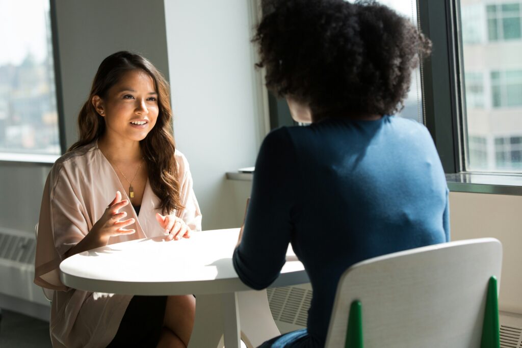 Two women talking to each other at a table.