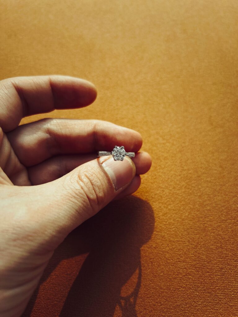 Hand holding a white gold engagement ring.