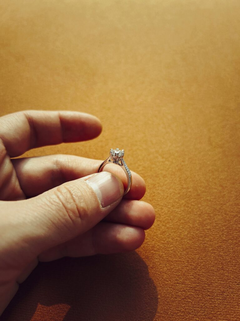 Hand holding a white gold engagement ring.