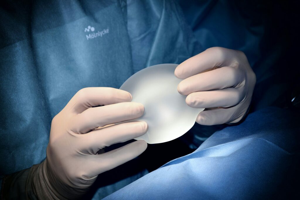 Certified plastic surgeon holding up breast implant.