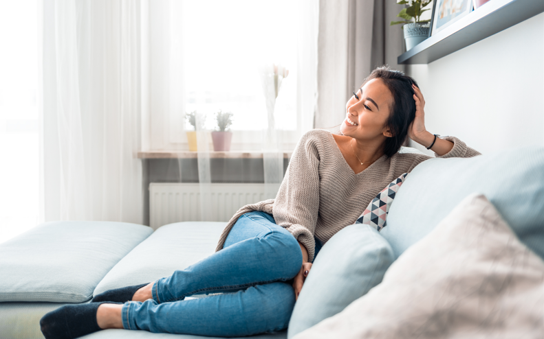 Woman sat on the sofa smiling.
