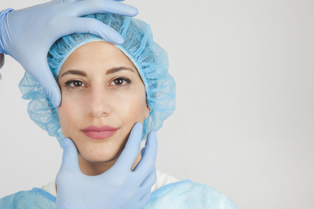 Woman wearing scrubs and a blue cap getting ready for aesthetic treatments.