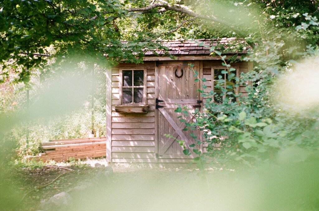 Image peeking through trees looking at a garden shed. This is to go with an article discussing floor thickness in sheds.