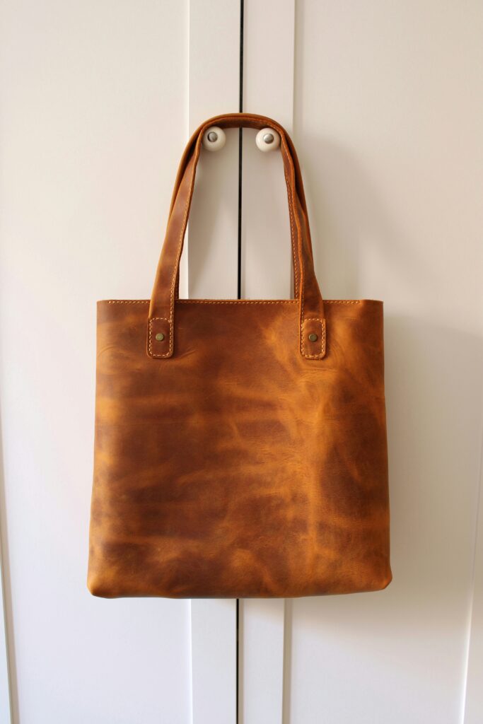 A brown leather tote bag hung up on wardrobe door knobs.