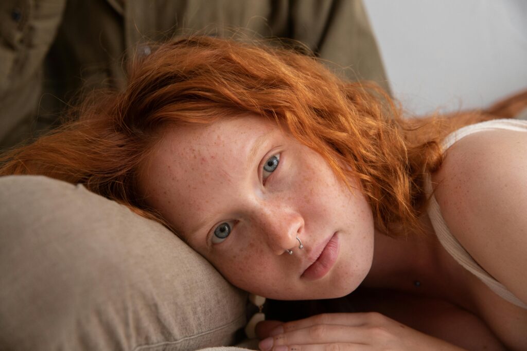 The art of looking polished. Woman with red hair and bare skin looking at the camera.