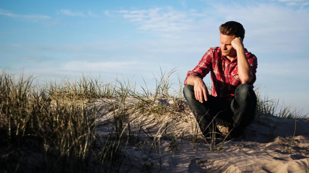 Man sat on a beach thinking about vasectomy reversal.