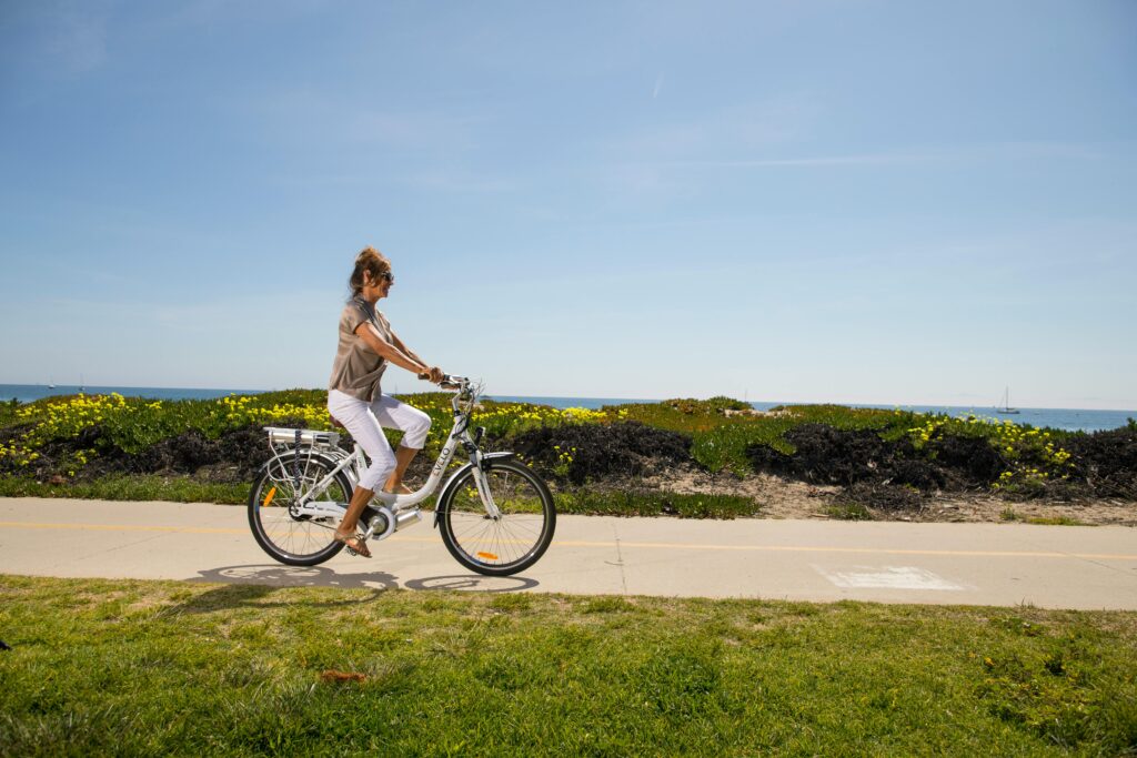 Woman riding bike along flat path.