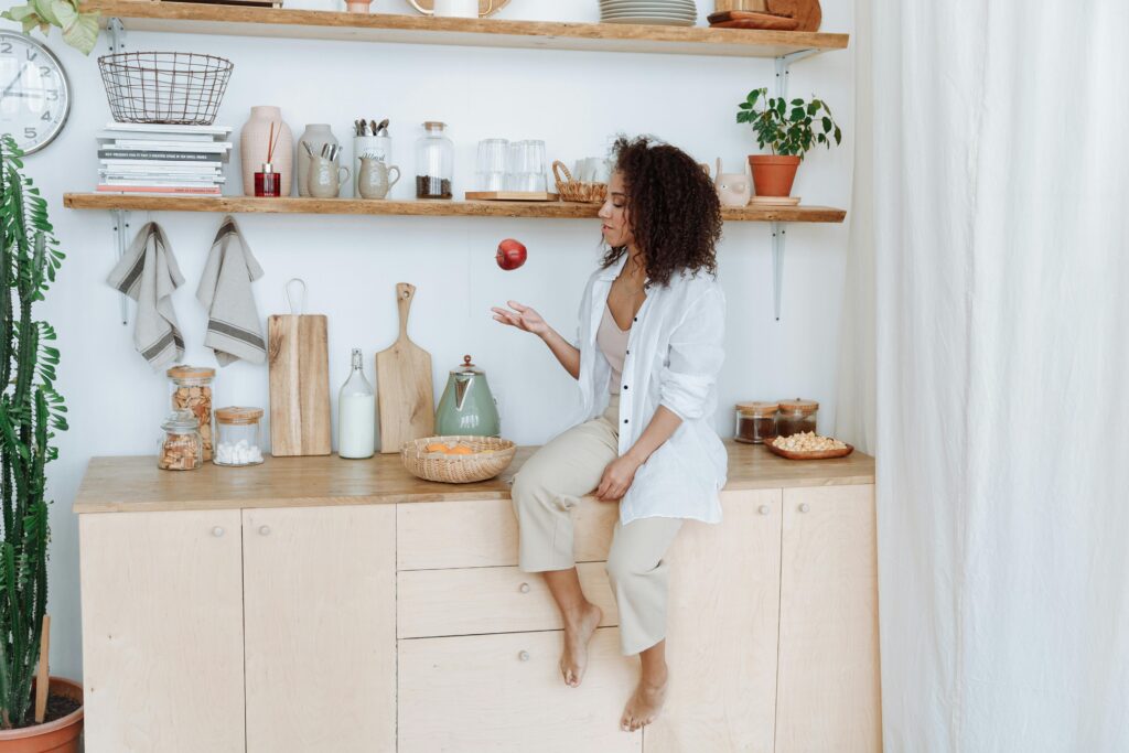 Woman sat in kitchen in a modern, neutral home.