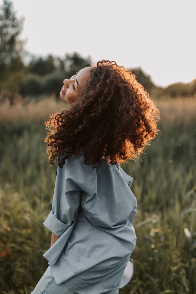 A carefree woman enjoying nature, showcasing happiness and freedom in a sunlit field.