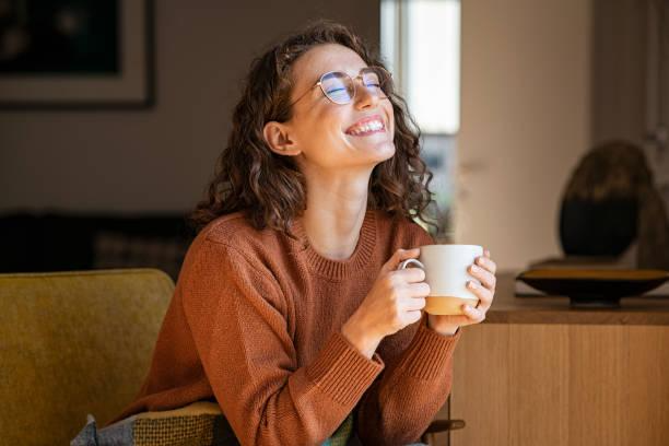 Autumn hair inspiration. Woman with brown curls in rust coloured jumper drinking coffee.