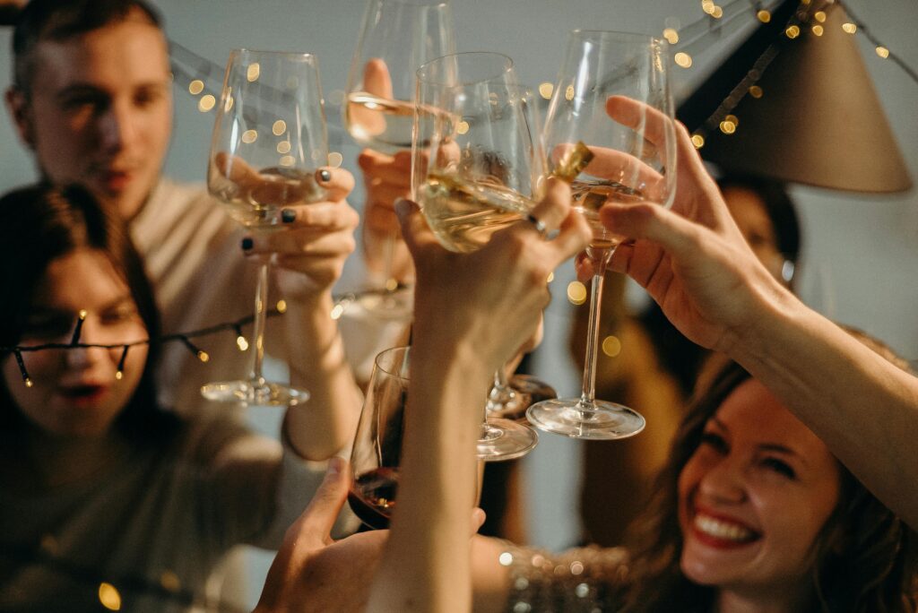 A group of people holding up glasses, cheersing to the ultimate Christmas party.