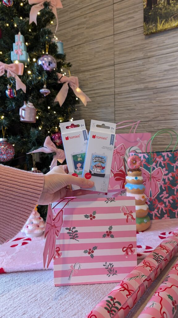 Placing 2 Tonie figures into a pink Christmas gift bag.