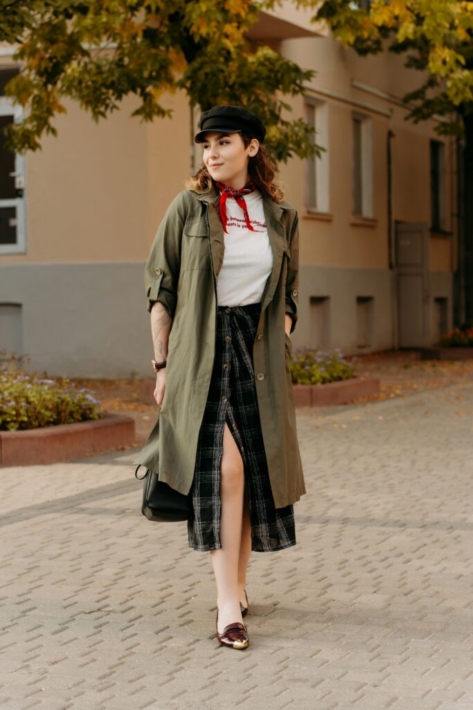 Woman wearing khaki longline coat and plaid midi skirt.