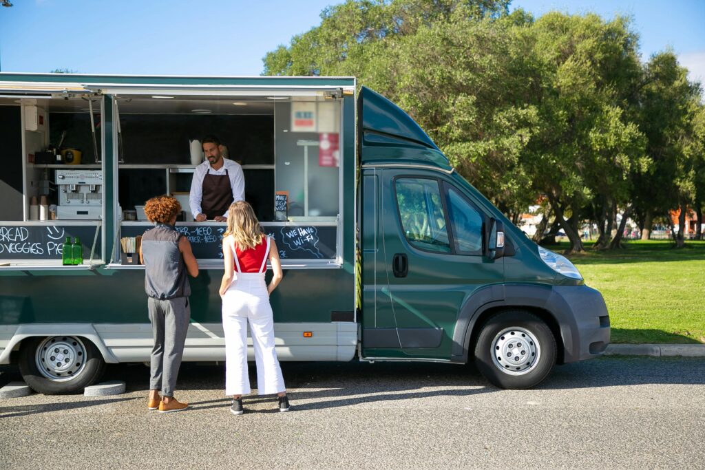 Food trucks with people standing outside waiting for food.