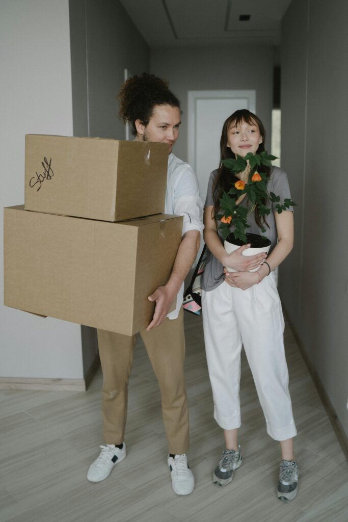 Couple moving house holding packing boxes.