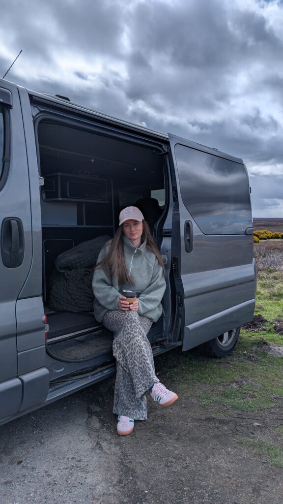 Claire Mac sitting in the doorway of a campervan.