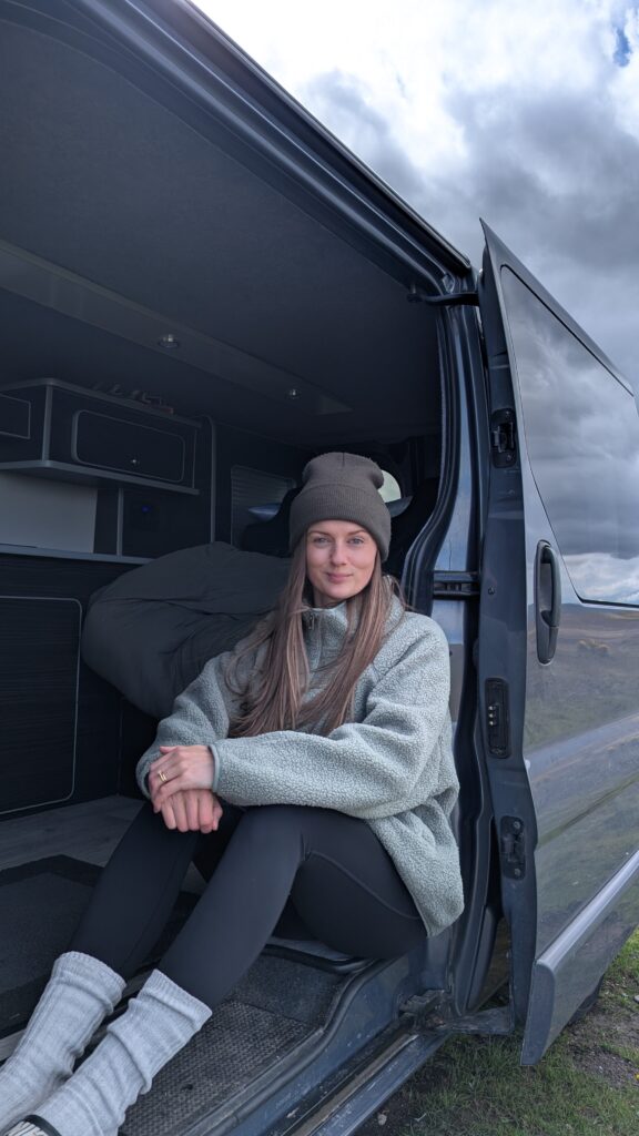 Claire Mac sat in the doorway of a campervan.
