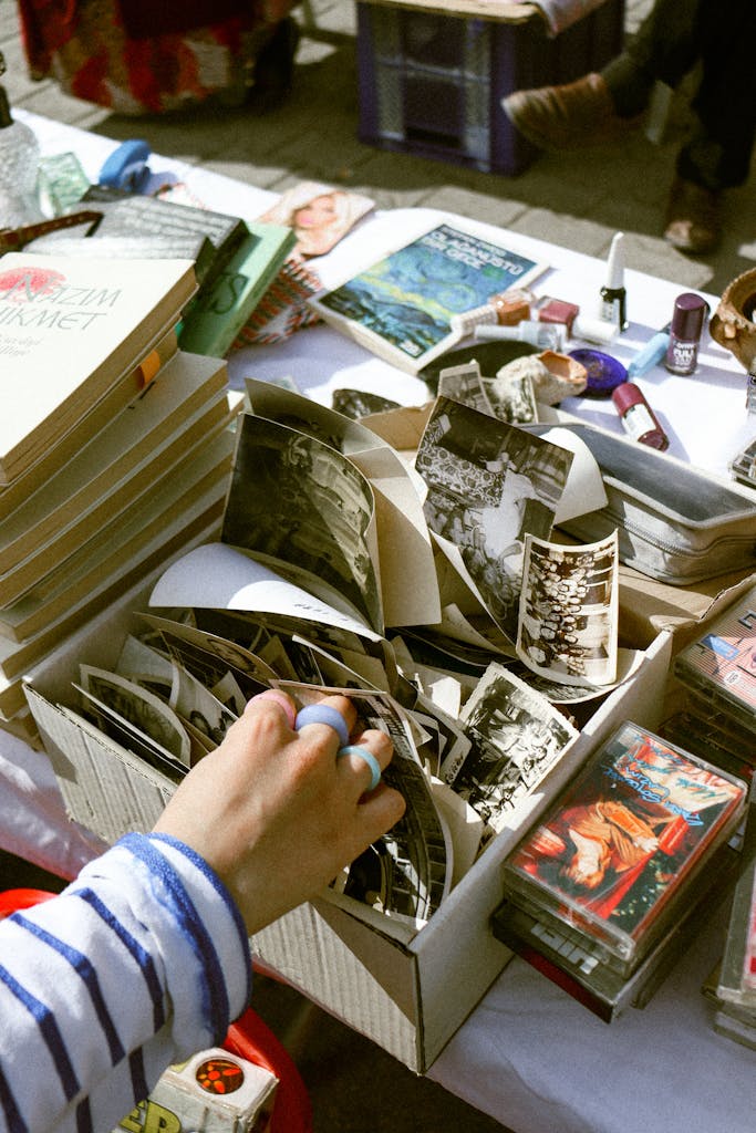 A person sifting through old photographs at a bustling outdoor flea market.