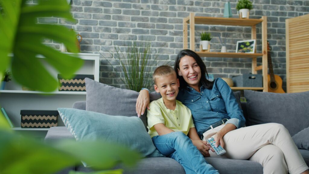 Mum and son sat together on a sofa. This is to go with a post giving examples of simple self-care habits for busy parents.