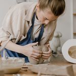 A woman focused on sculpting clay during an art workshop, showcasing her skills and creativity.