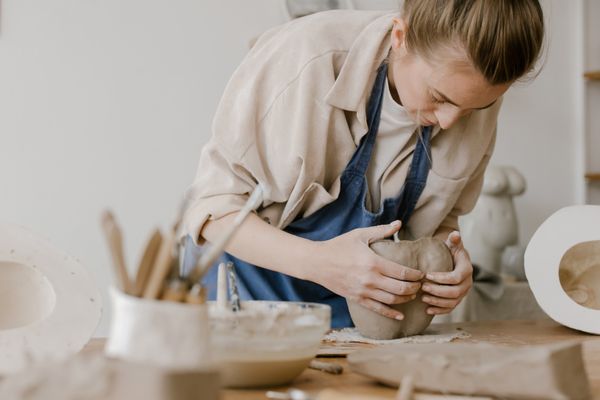 A woman focused on sculpting clay during an art workshop, showcasing her skills and creativity.