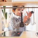 A young child having fun exploring kitchen utensils in a cozy indoor setting.