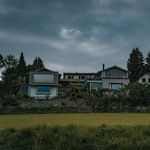 Stylish suburban houses with lush greenery beneath a dramatic cloudy sky, perfect for architecture and landscape themes.